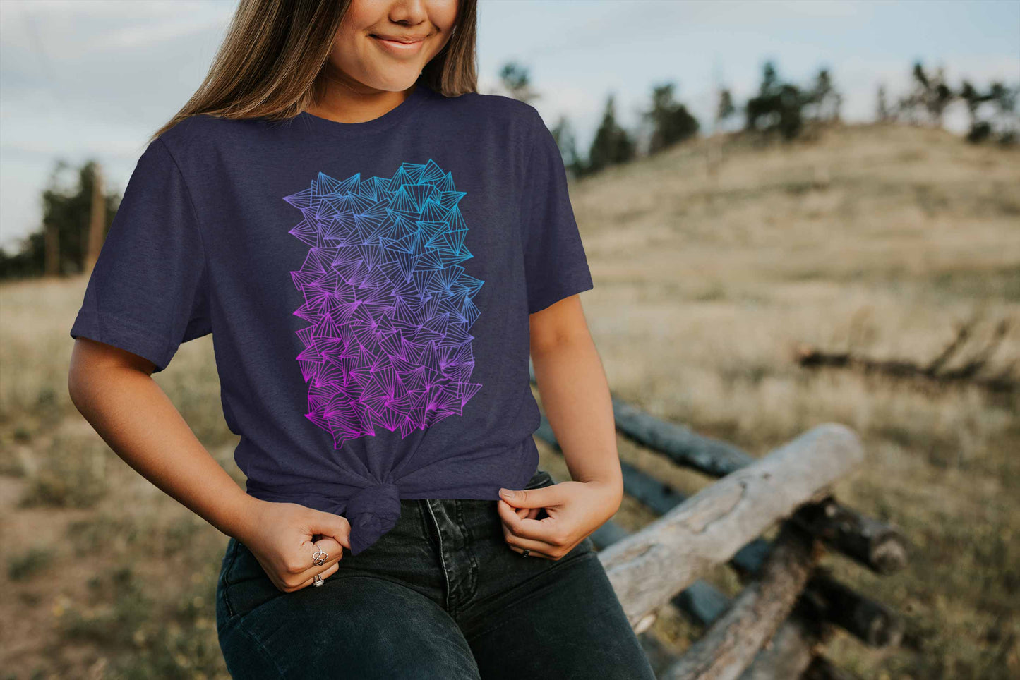 Model posing in a field with gaggle of triangles gradient design on heather midnight navy unisex t-shirt.