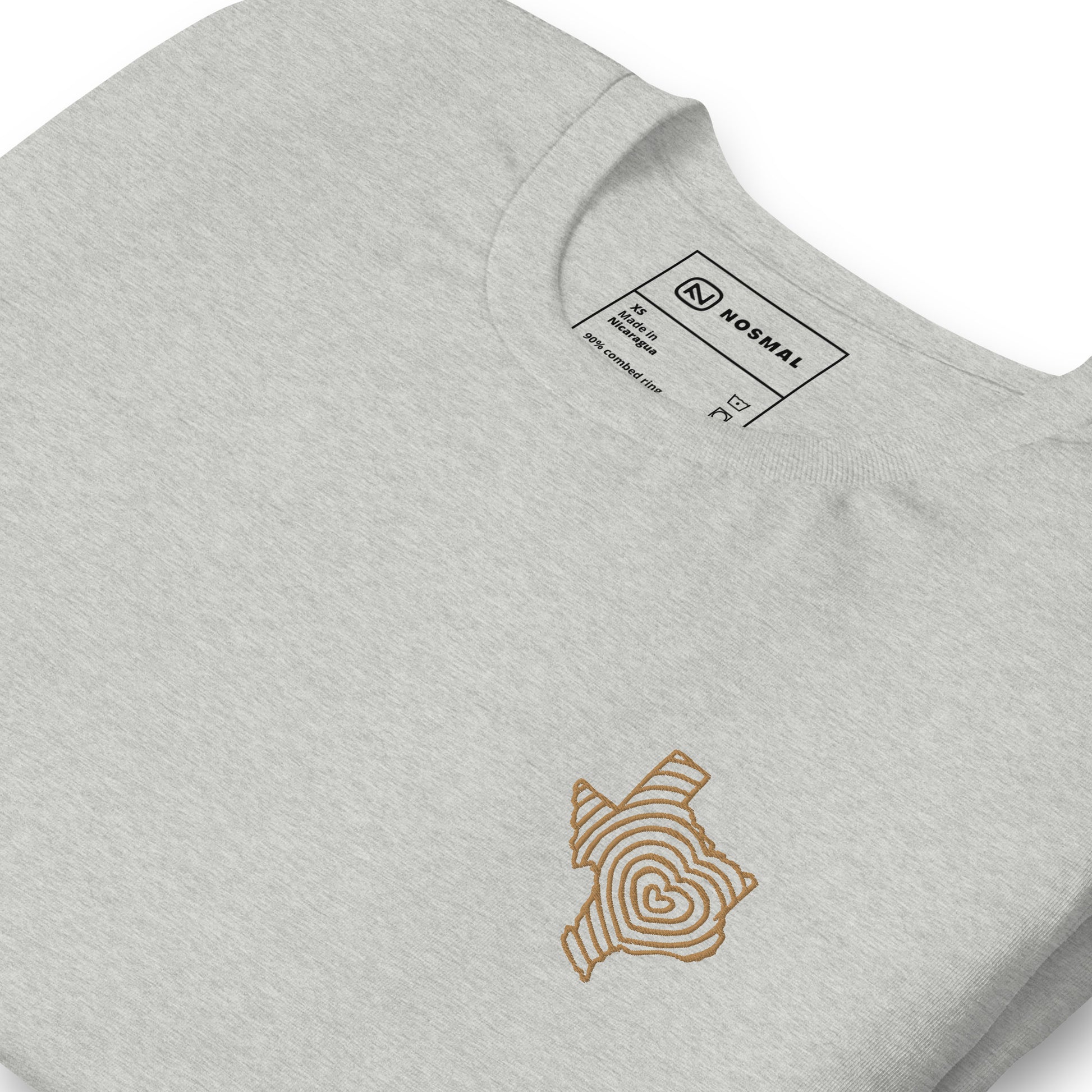 Angled close up shot of heartbeat of texas gold embroidered design on heather athletic grey unisex t-shirt.