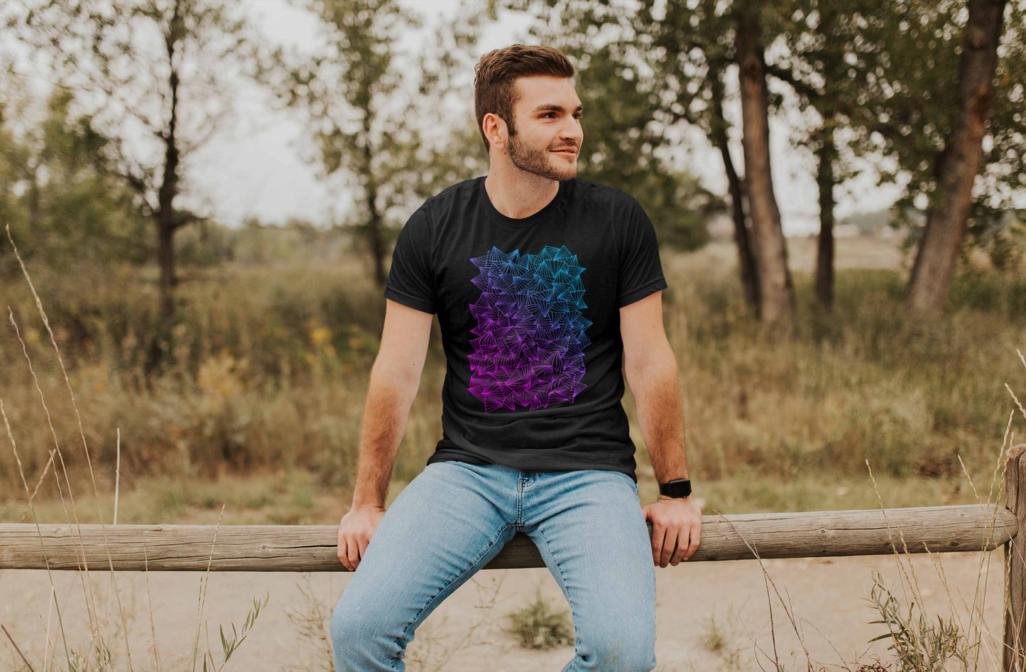 Model posing in a field with gaggle of triangles gradient design on heather black unisex t-shirt.