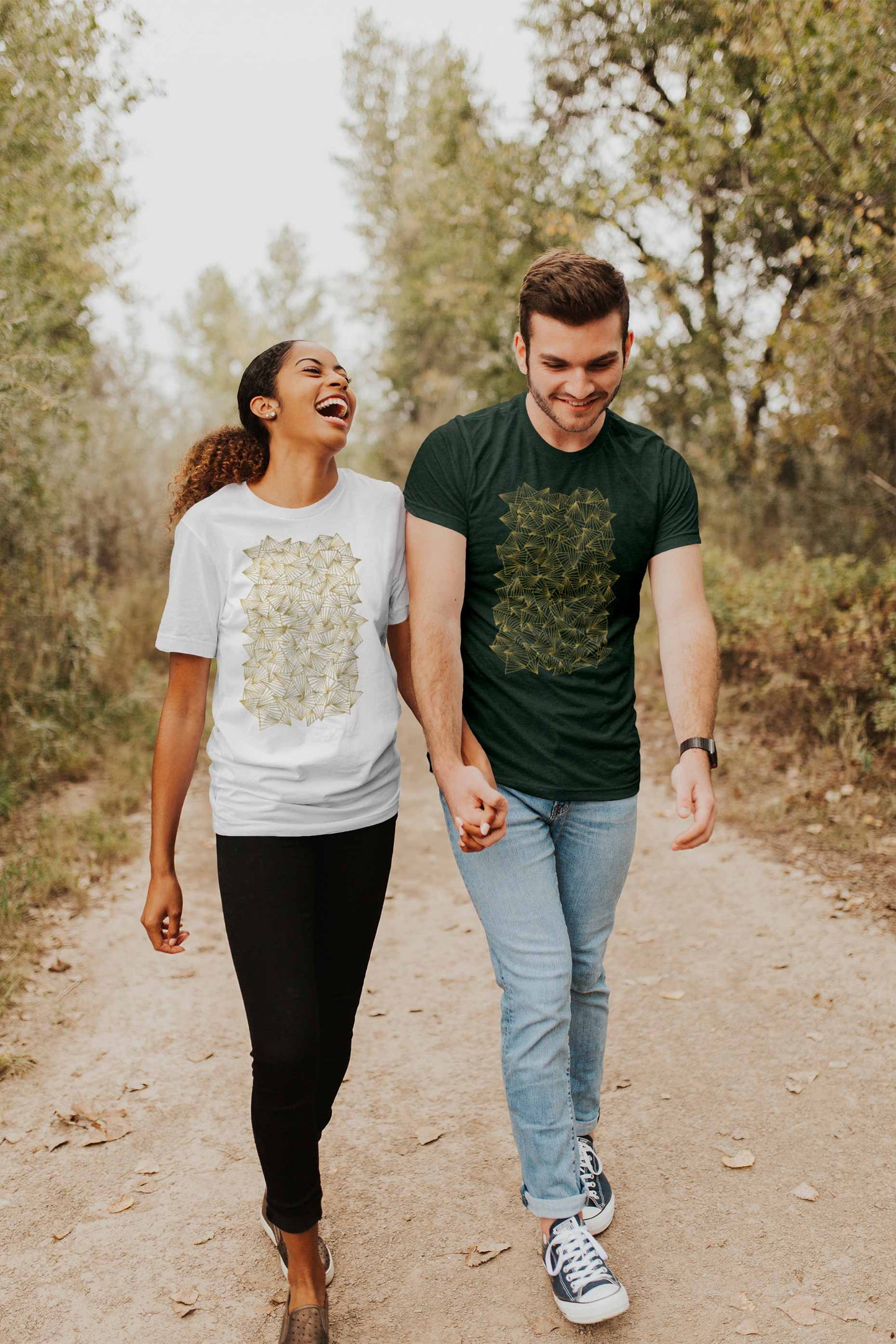 Couple walking in the woods with gaggle of triangles gold design on a white and heather forest graphic tees.