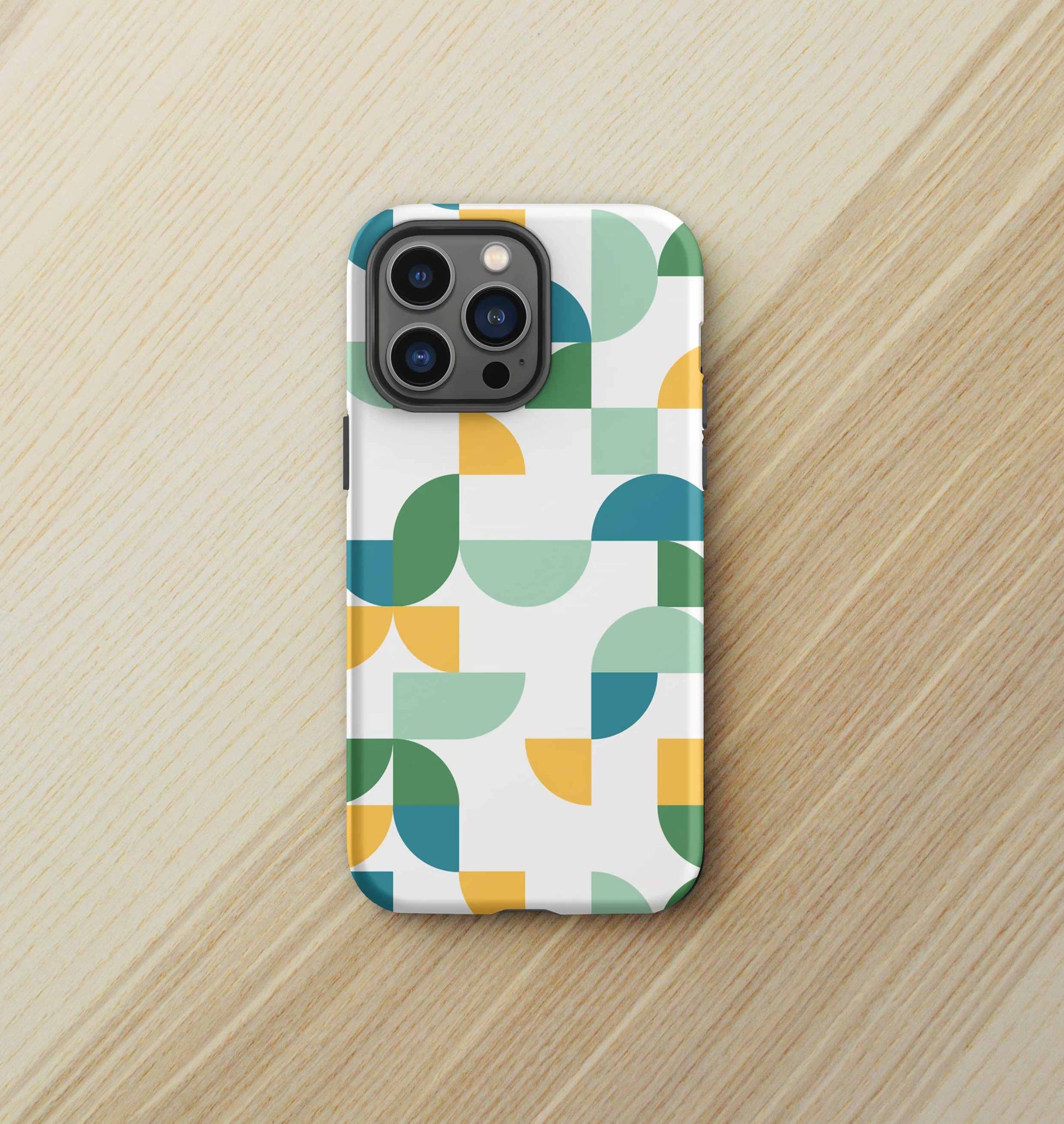 Front view of iPhone tough case in Geometria I Midday design on a birch desktop