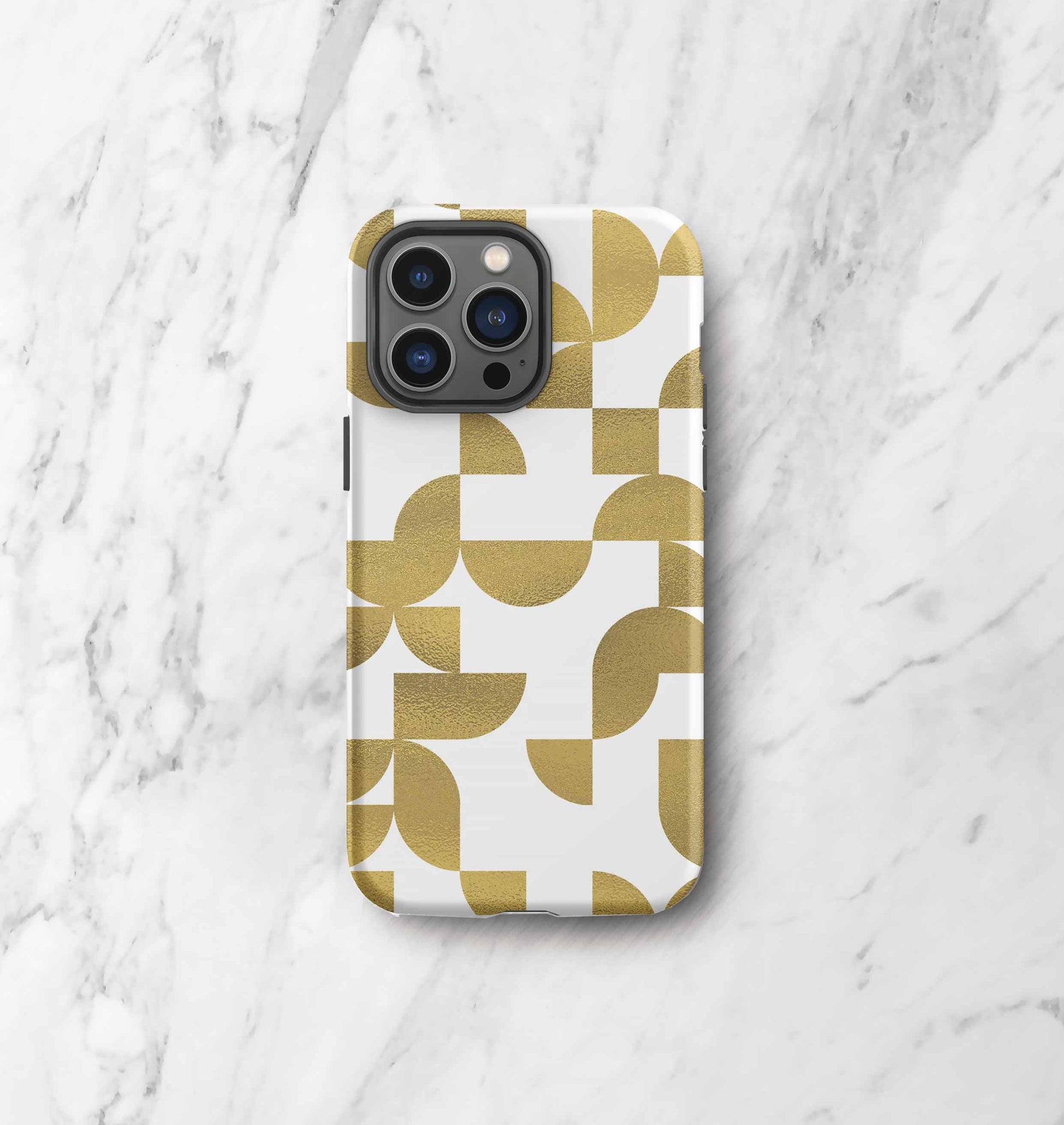 Front view of iPhone tough case in Geometria I gold design on a marble countertop
