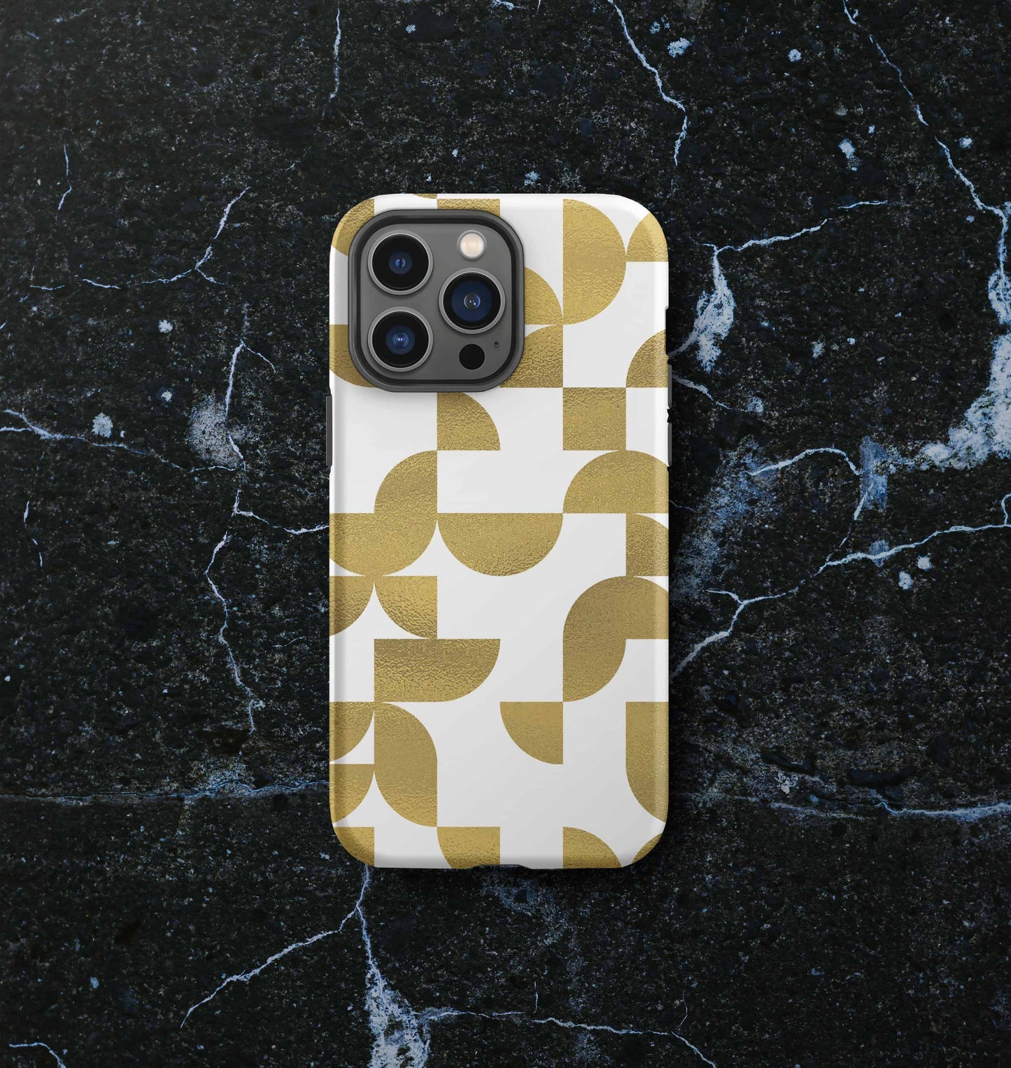 Front view of iPhone tough case in Geometria I gold design on a slate countertop