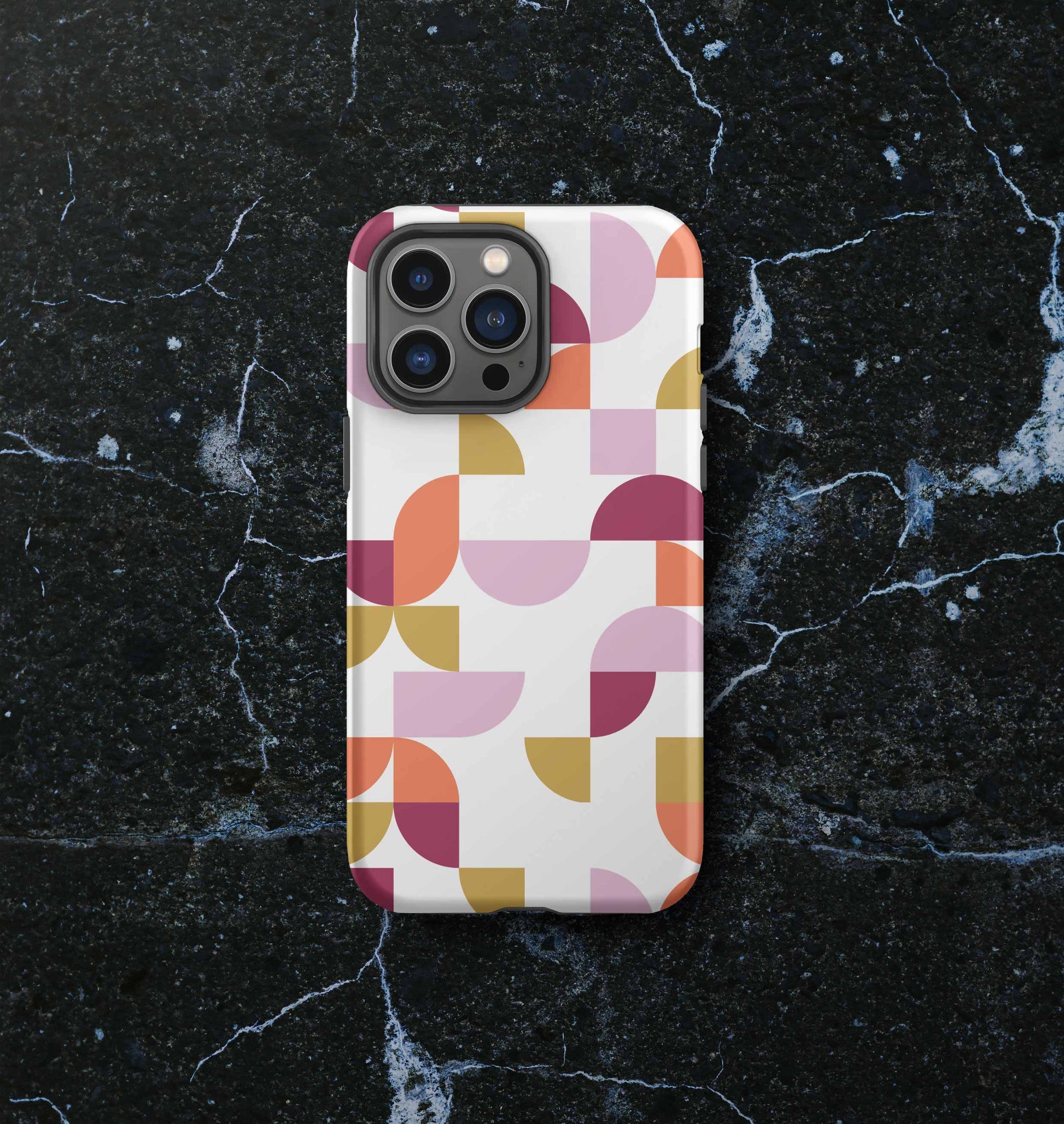 Front view of iPhone tough case in Geometria I Sunset design on a slate countertop