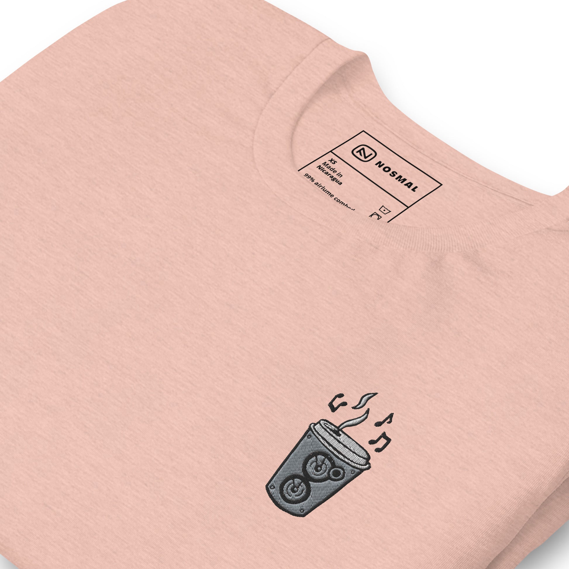 Angled close up shot of the coffee is my jam embroidered designon heather prism peach unisex t-shirt.